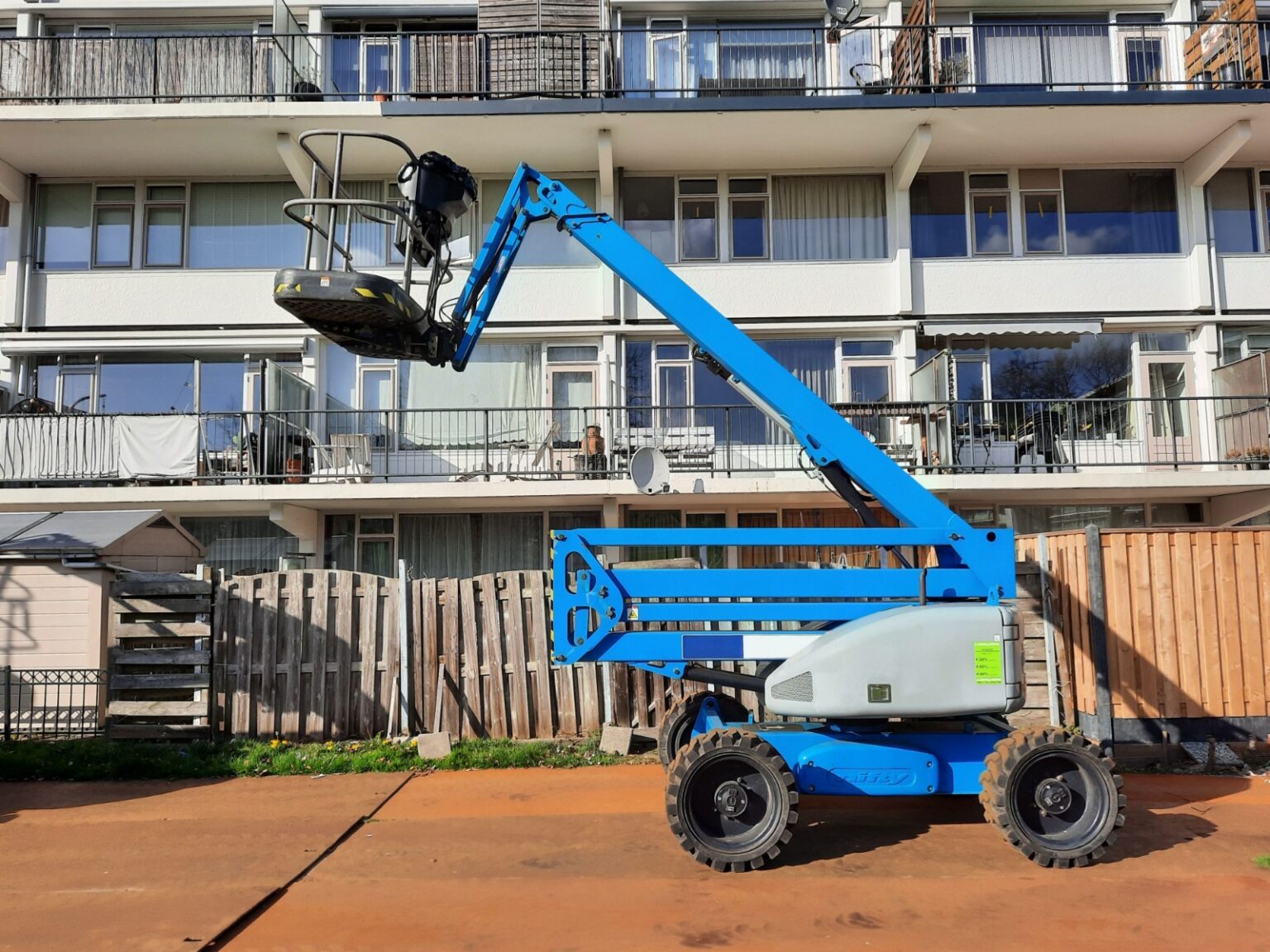 Electric scissor lift in Umm Al Quwain operating at a construction site with safety rails extended for elevated work.